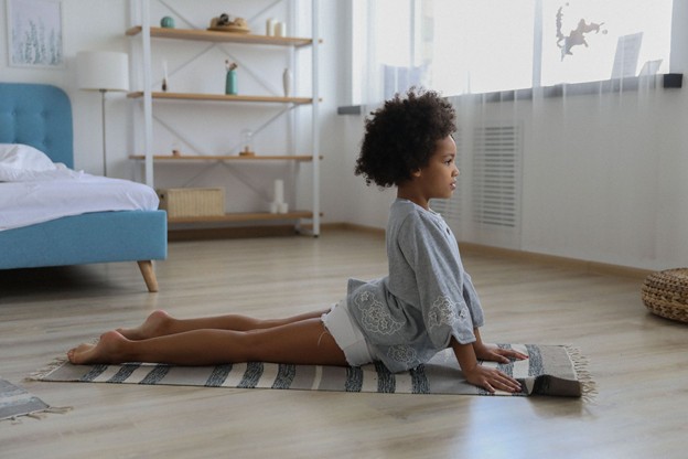 Young girl doing a yoga pose in her room.